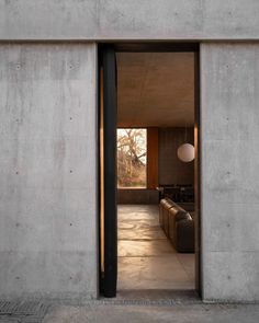 an open door leading to a living room with couches and lamps on the wall