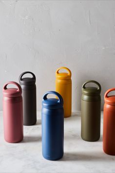 four different colored canisters sitting next to each other on a white countertop