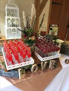 a table topped with lots of glasses filled with liquid and strawberries on top of it