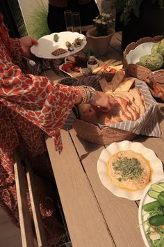 a woman in an orange and white dress is serving food on a table with plates