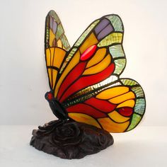 a stained glass butterfly sitting on top of a rock