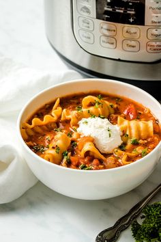 a bowl of pasta soup next to an instant pot