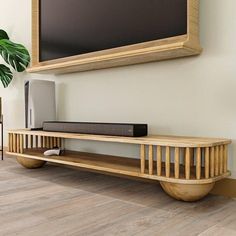 a tv is mounted on the wall next to a shelf with speakers and a plant