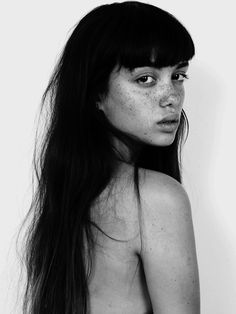 a black and white photo of a woman with freckles on her body, looking at the camera