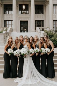 a group of women standing next to each other in front of a building with white flowers