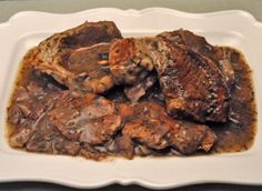 a white plate topped with meat covered in gravy