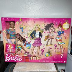 barbie dolls are on display in front of a pink box with question marks and numbers