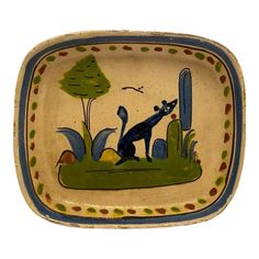 a decorative bowl with a dog on it's side and trees in the background