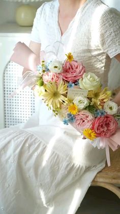 a woman sitting on a chair holding a bouquet of flowers