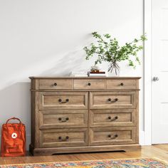 a wooden dresser sitting on top of a hard wood floor next to a white door