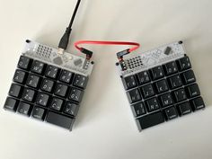 two keyboards with wires attached to them sitting next to each other on a white surface