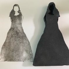 two black and silver dresses on display against a white background, one in the shape of a woman's dress