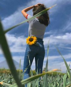 a woman standing in a field with a sunflower