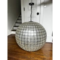 a metal ball hanging from a chain on a wooden floor in front of a door