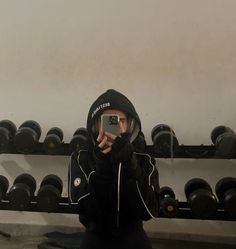 a man is taking a selfie in front of a rack of dumbbells