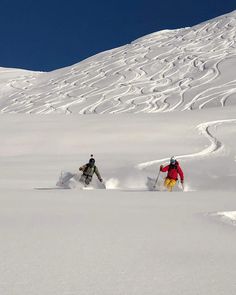 two people skiing down a snowy mountain side