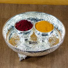 two bowls filled with different colored powders on a silver plate