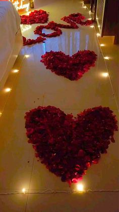 two hearts made out of roses on the floor with candles in the background and lights around them