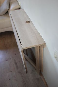 a wooden table sitting on top of a hard wood floor next to a white couch