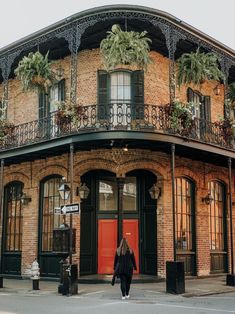 a woman walking down the street in front of an old brick building with wrought iron balconies