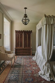 a bedroom with a canopy bed, chair and rug on the floor in front of it