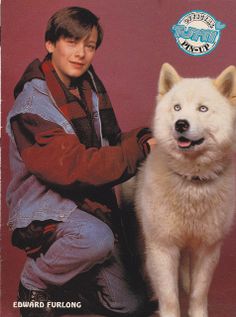 a young man sitting next to a white dog on top of a magazine cover,