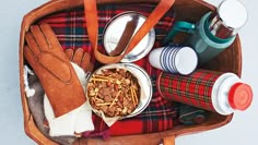 a wooden bowl filled with food on top of a plaid cloth covered table next to coffee cups