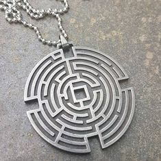 a necklace that has a maze in it on a concrete surface with a chain attached to it