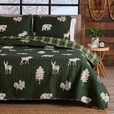 a bed covered in green and white bedspread with moose designs on the sheets