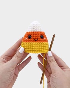 two hands holding up a small crocheted toy with chopsticks in front of it