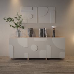 a white sideboard with vases and books on it next to a plant in a vase