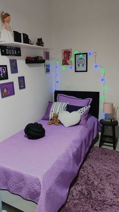 a purple bed in a white room with pictures on the wall and lights above it