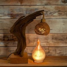 a wooden table topped with a lamp next to a vase and a tree branch on top of it