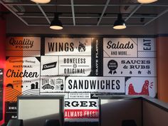 an empty restaurant with signs on the wall and lights hanging from the ceiling above them