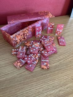 pink and white dice sitting on top of a wooden table next to a red box