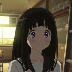 a girl with long black hair standing in front of a window looking at the camera