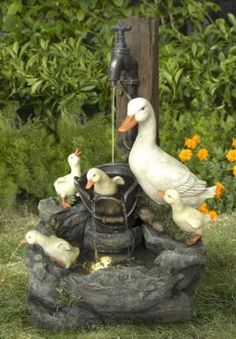 ducks and geese drinking water from a faucet in a garden with orange flowers