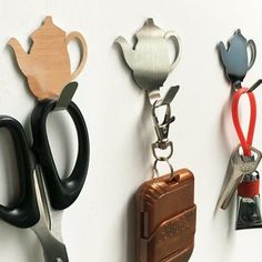 three pairs of scissors hanging from hooks on a wall with other items attached to them