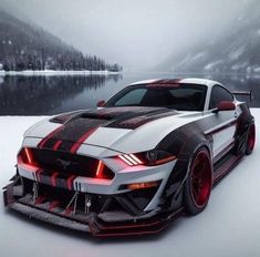 a white and black mustang with red stripes on it's hood in the snow