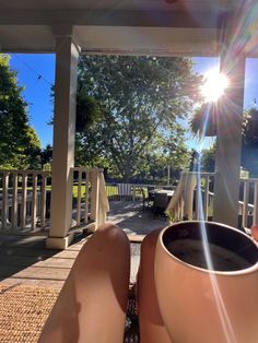 someone is sitting on the porch with their feet propped up and holding a coffee cup