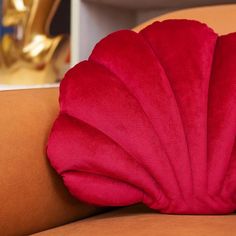 a red pillow sitting on top of a couch next to a gold statue in the background