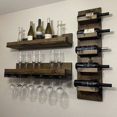 several wine glasses and bottles are lined up on wooden shelves in front of a white wall