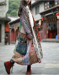 a woman is walking down the street wearing a colorful coat and boots with her hands in her pockets