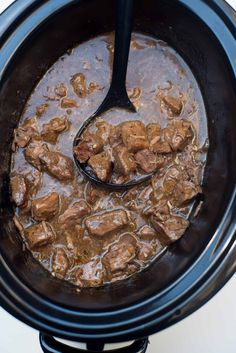 beef stew in the slow cooker with a ladle scooping it into the pot