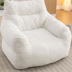 a large white chair sitting on top of a rug in a living room next to a window