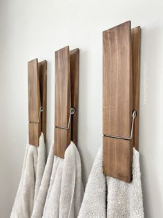 three towels are hanging on the wall near two towel racks and one is made out of wood