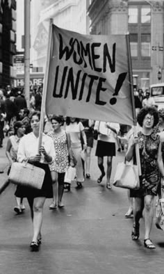 people walking down the street holding signs that read women united