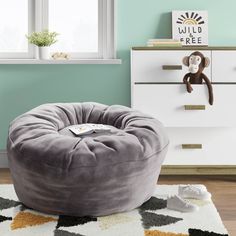 a large grey bean bag chair sitting on top of a rug in front of a window