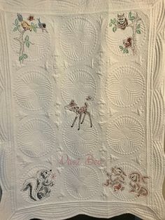 a white quilt with embroidered animals on it