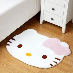 a hello kitty rug is on the floor next to a white bed and nightstands